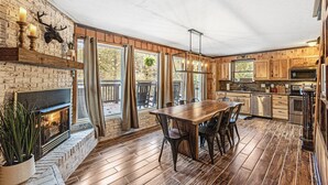 A spacious kitchen with wooden cabinets, a large dining table, and a fireplace.