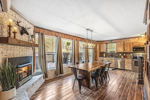 Eine geräumige Küche mit Holzausstattung, einem großen Esstisch und einem Kamin.