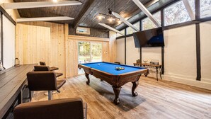 A pool table in a room with wooden walls and a large window.