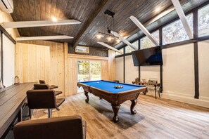 A pool table in a room with wooden walls and a large window. - Large cabin near boat rentals & Nantahala with Hot Tub, Pool Table, & Gameroom (Bryson City)
