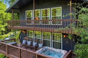 Une maison en bois à deux étages, dotée d’un balcon, d’un espace salon extérieur et d’un jacuzzi.