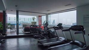 A gym with treadmills, a rowing machine, and a bench press area, with a city view through large windows. - 1BR|1BA Apartment W/ pool, gym, high speed WiFi, located just a 3-minute walk from the new U.S. Embassy (Ciudad de México)