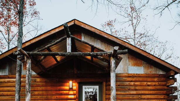 A wooden cabin with a green door, a wooden porch, and a metal roof. - Firefly Treehouse - Starlight Haven (Hot Springs)