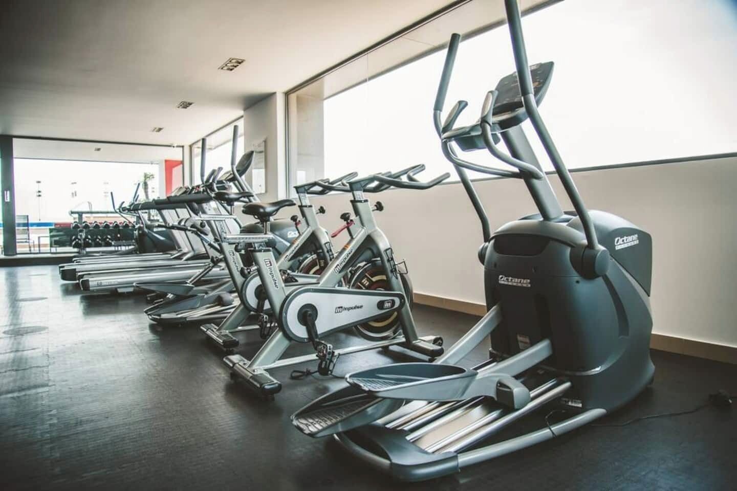 Een fitnessruimte met hometrainers en loopbanden.