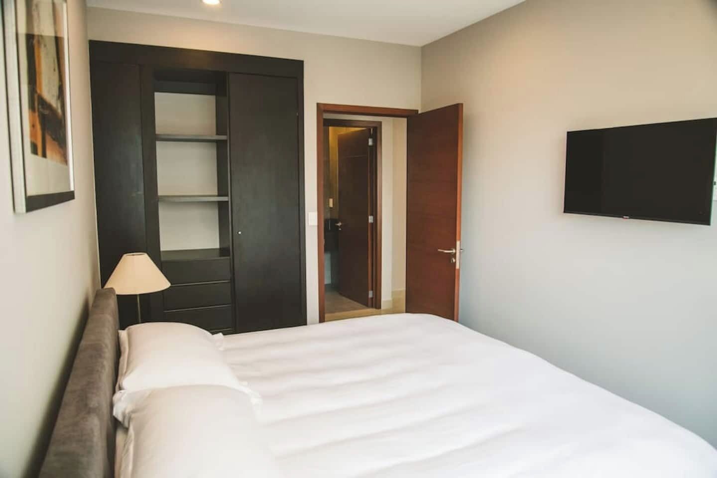 Ein Hotelzimmer mit Bett, Schrank, Tür und Fernseher an der Wand.