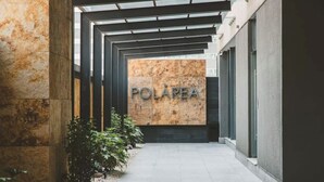 Un couloir avec une enseigne indiquant « POLÁREA » et une architecture moderne caractérisée par un plafond de verre et des murs en pierre.
