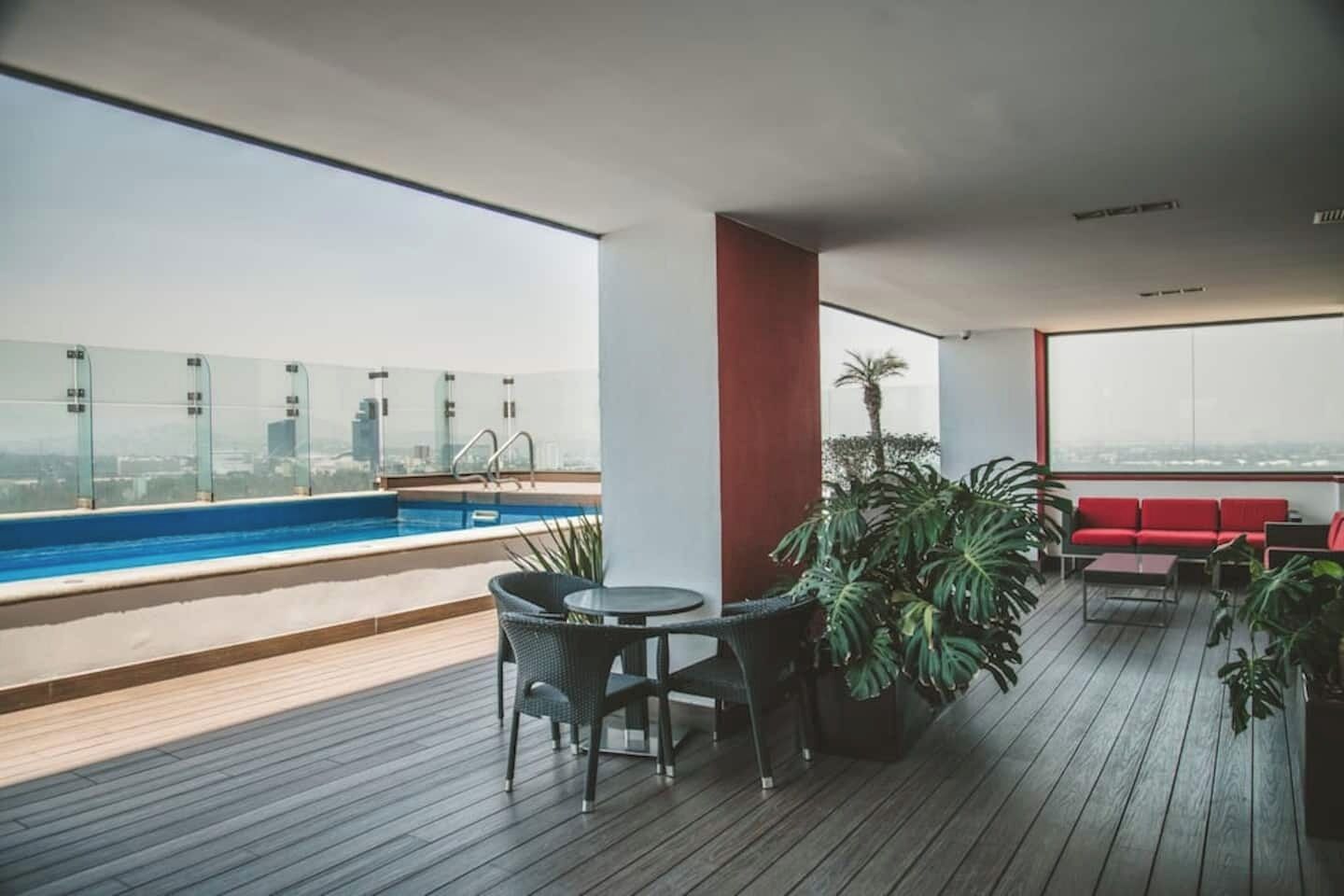Eine Dachterrasse mit Pool, Sitzgelegenheit und Topfpflanzen.