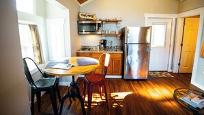 Una cucina compatta con un tavolo di legno, sedie, un frigorifero, un forno a microonde e una macchina per il caffè.