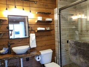 Un baño de madera con lavamanos, inodoro y cabina de ducha de vidrio.