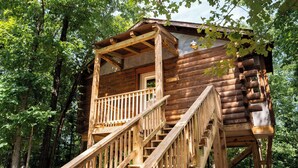 A wooden cabin with a staircase leading to a balcony. - Mountain Air Treehouse - Starlight Haven (Hot Springs)