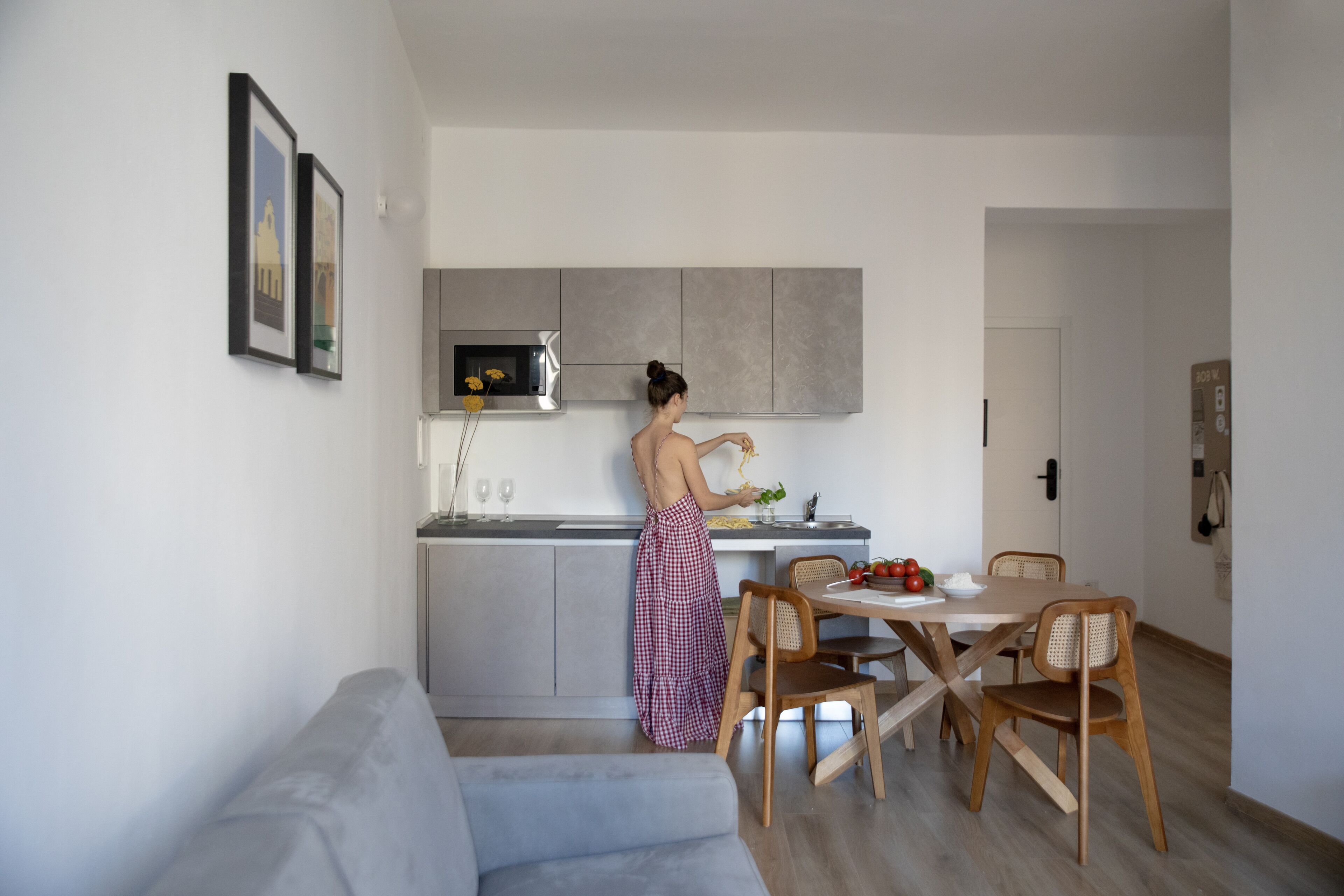 A modern kitchen with a built-in microwave and grey cabinets. A person is preparing food at the counter.