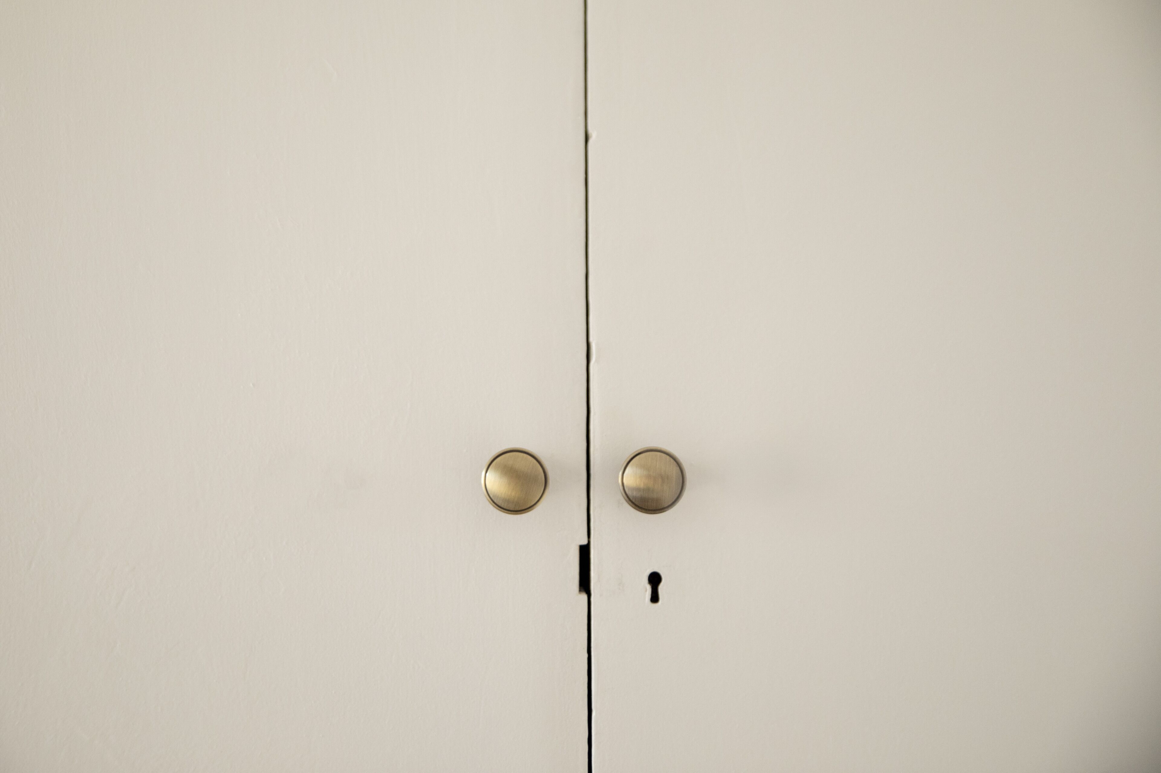 Una puerta blanca con dos pomos de latón redondos y una cerradura.