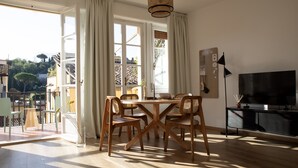 Een ruime woonkamer met een houten eettafel, stoelen en een televisie.
