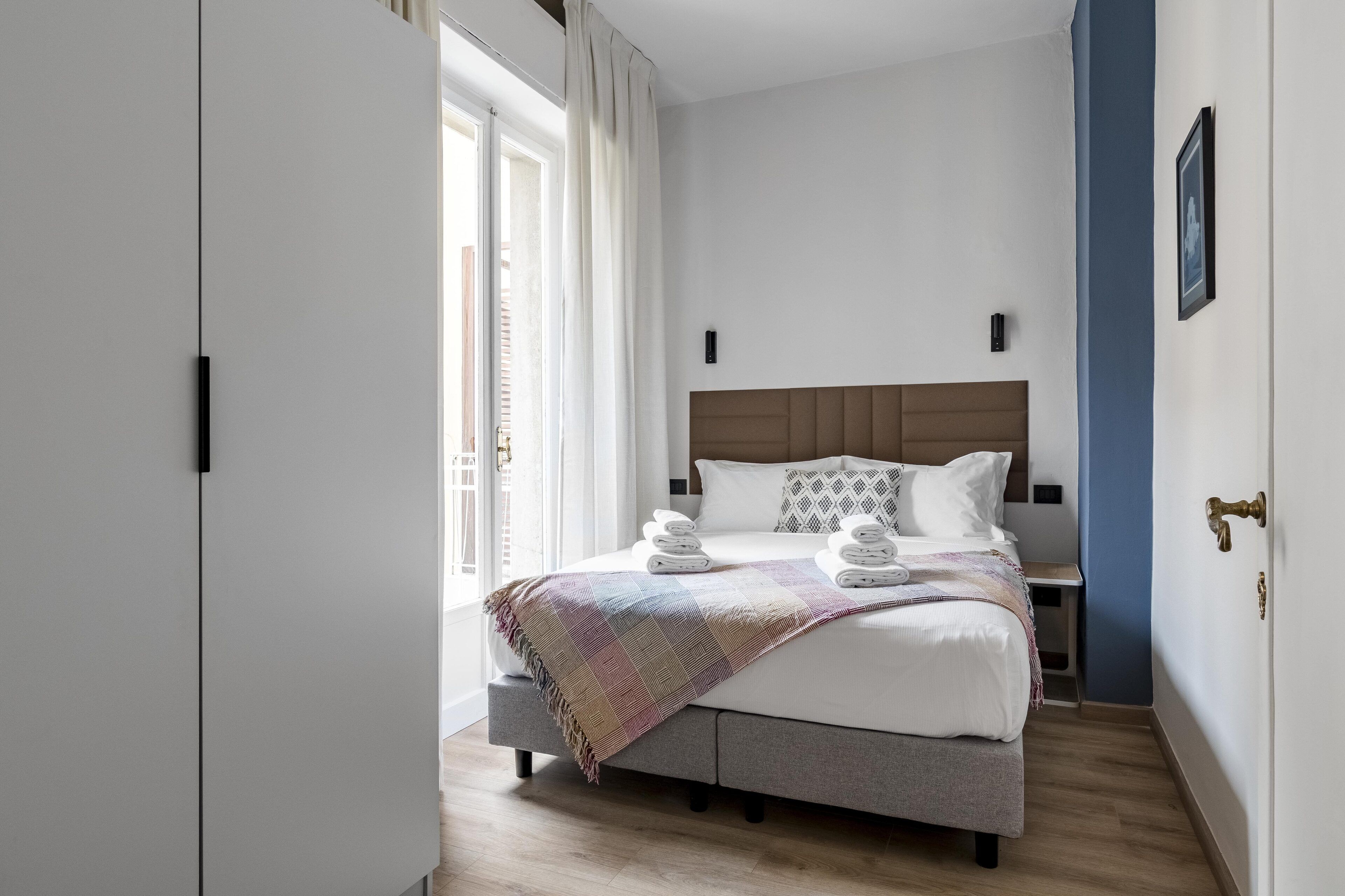 Un dormitorio moderno con una cama grande, una mesita de noche y una ventana con cortinas.