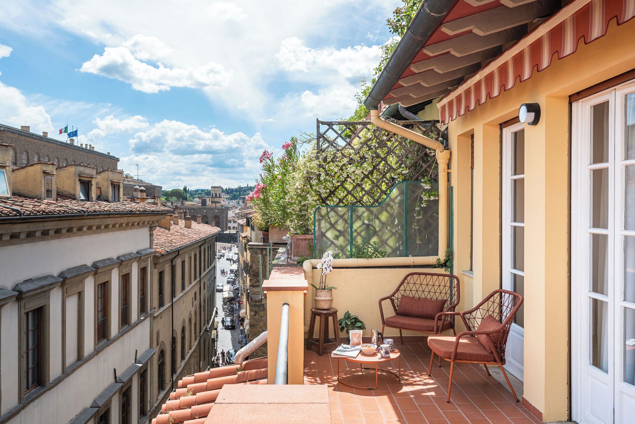 A balcony with a view of the city, a small table with a chair, and a potted plant.