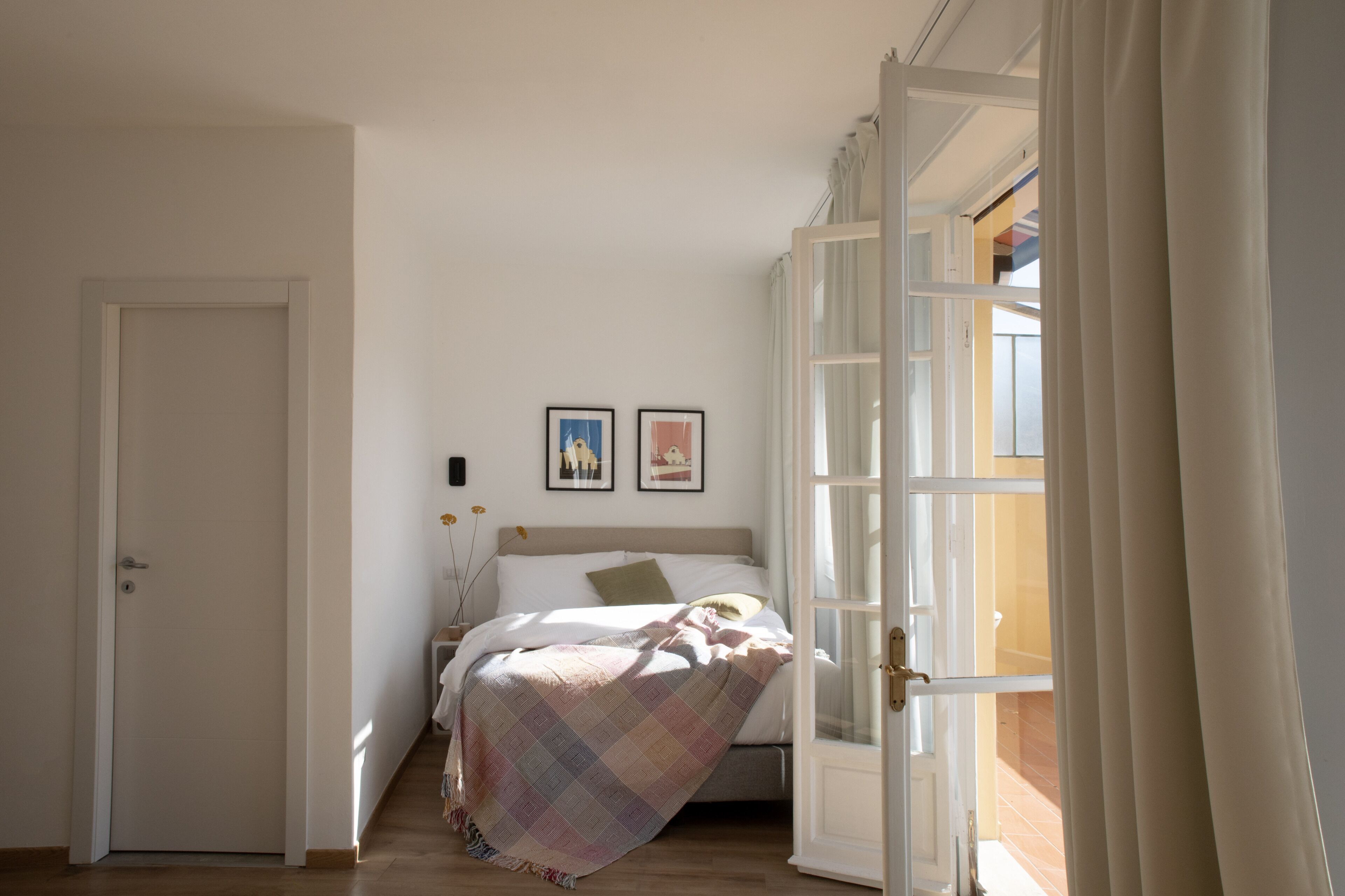 A bedroom with a bed, a door, and a window.