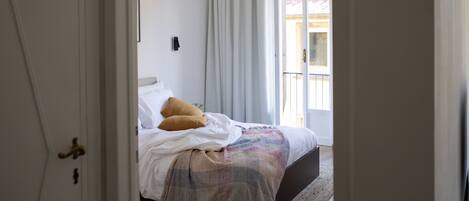 A bedroom with a bed, a door, and a view of the outside.