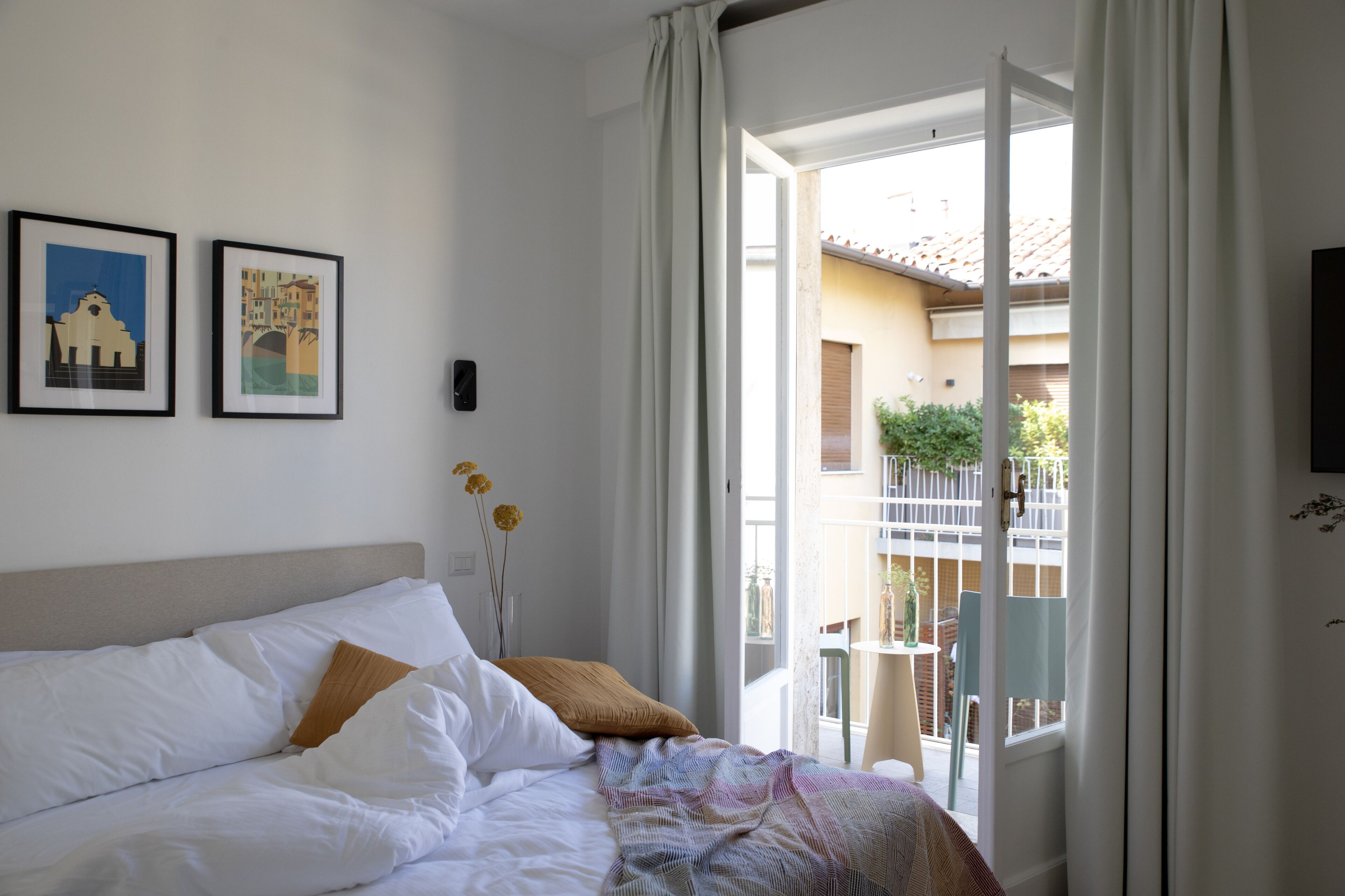 Ein Hotelzimmer mit Bett, einem Fenster mit Vorhängen und zwei gerahmten Bildern an der Wand.
