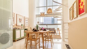A modern dining area with a wooden table and chairs, a green cabinet, and framed artwork on the walls.