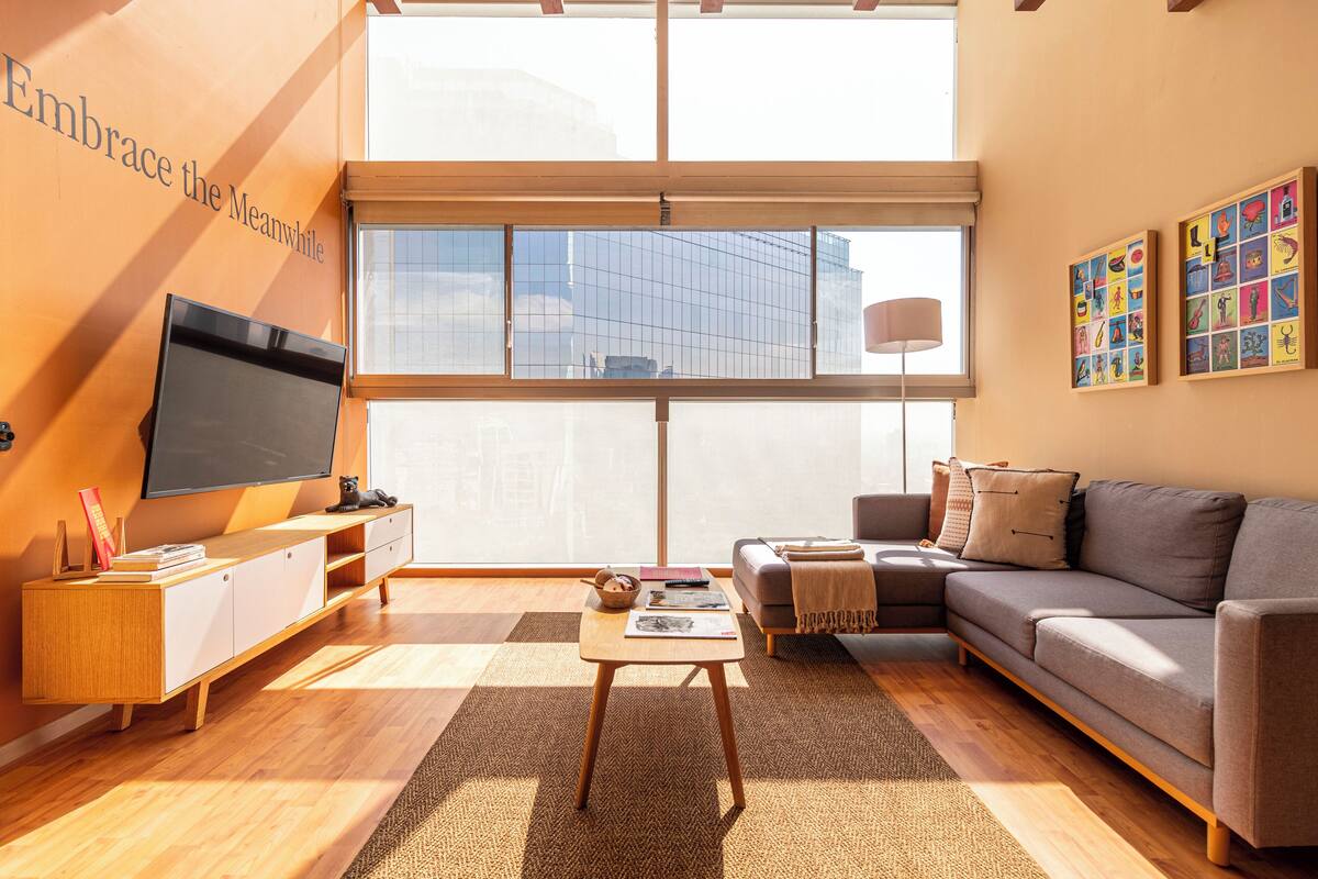 A modern living room with a large window, a flat-screen TV, a sofa, and a coffee table.