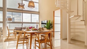A spacious living area with a dining table, chairs, and a modern staircase.