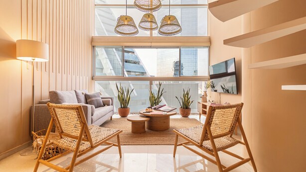 A modern living room with a sofa, two wicker chairs, a coffee table, and potted plants.