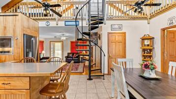 A spacious kitchen with a central island, wooden cabinets, and a spiral staircase connecting to an upper level.