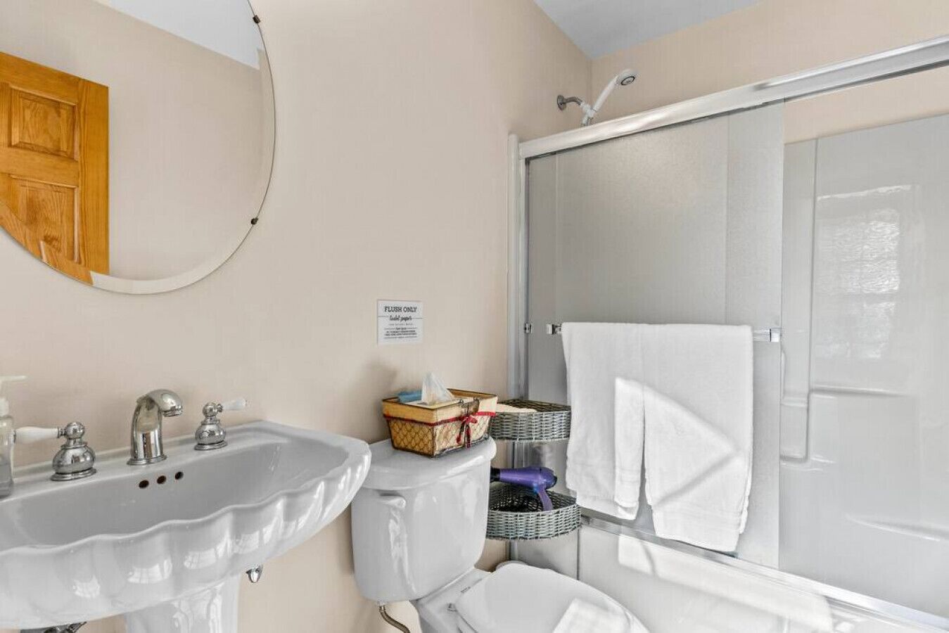 A bathroom with a sink, mirror, and shower.