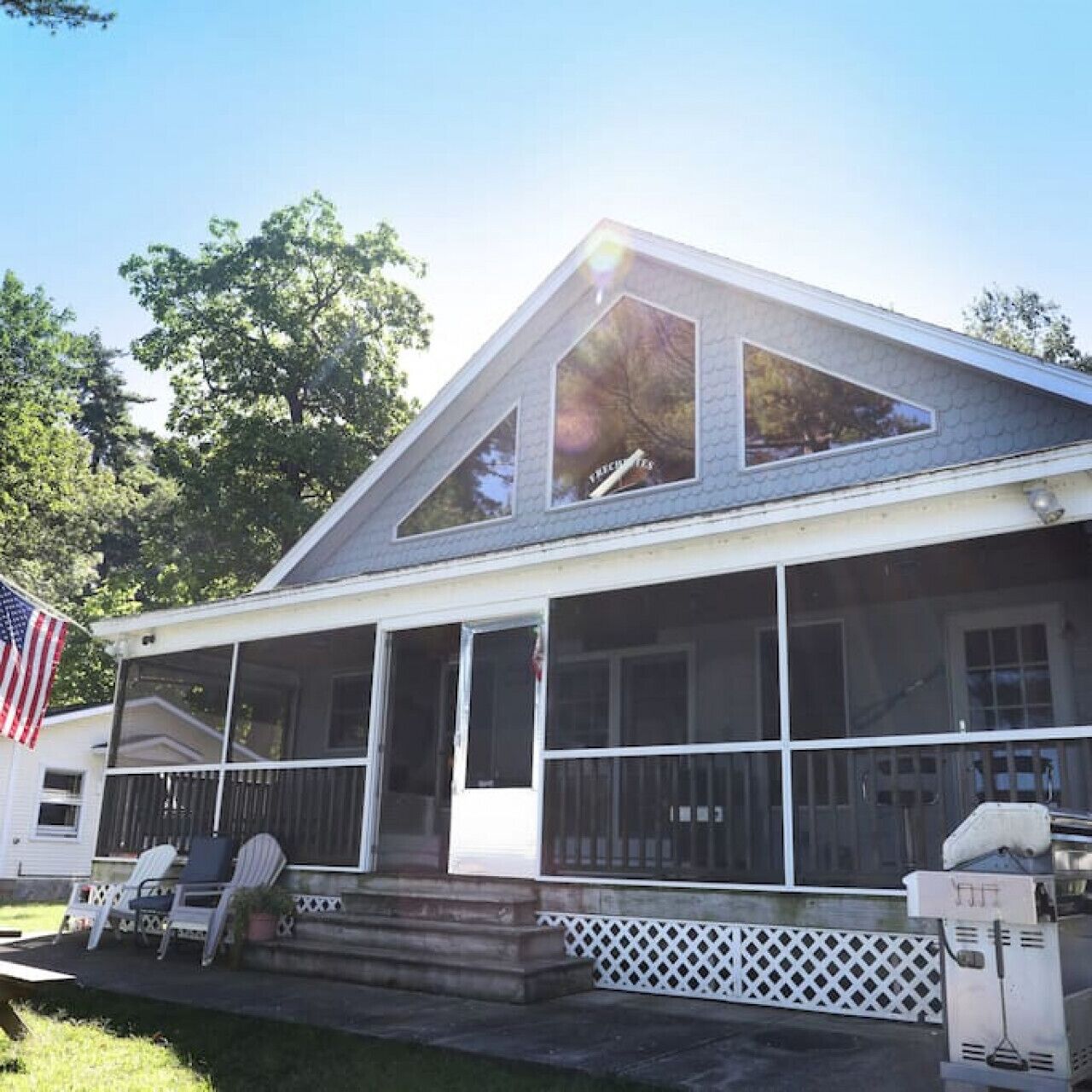 A house with a sloped roof, large windows, and a porch with chairs.