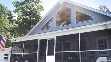 A house with a sloped roof, large windows, and a porch with chairs.