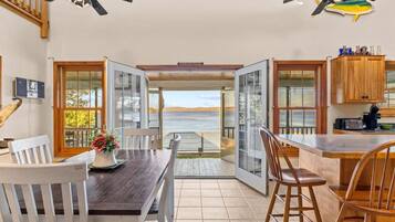 A dining area with a view of the sea, wooden furniture, and ceiling fans.