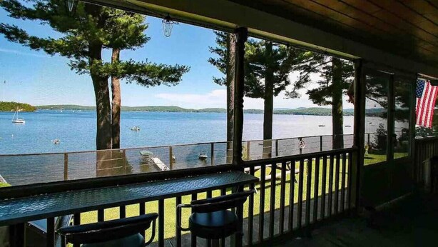 A covered outdoor seating area with a view of a lake and a dock. - Cottage · Beachfront Cottage on Lake Champlain, Colchester (Colchester)