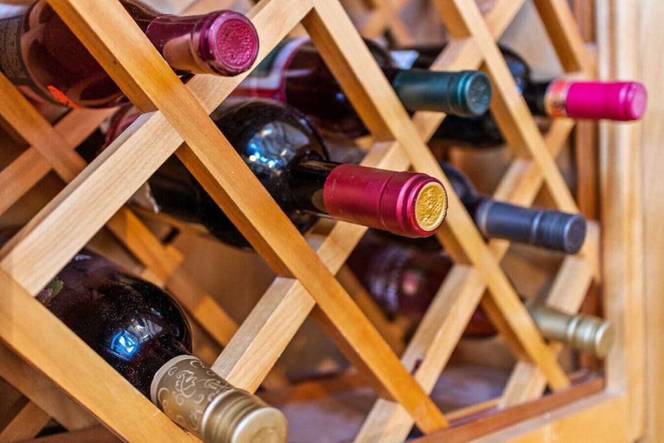 A wooden wine rack with multiple bottles.