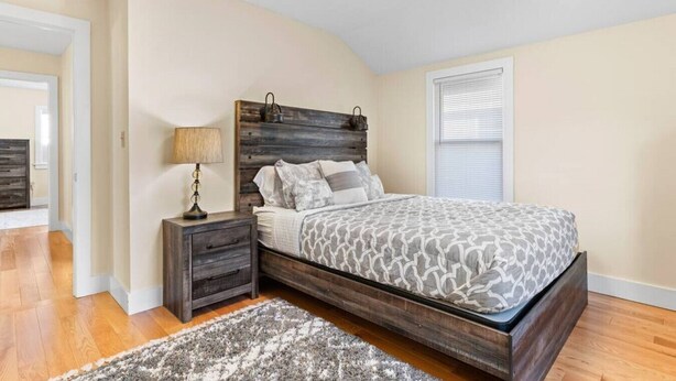 A bedroom with a bed, nightstand, lamp, and a rug.