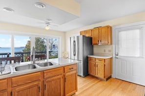 A kitchen with wooden cabinets, stainless steel appliances, and a view of the sea.