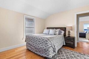 A bedroom with a bed, bedside table, and a view of a balcony.