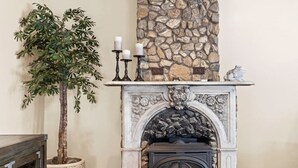 Una chimenea con repisa de piedra, una planta en maceta y un candelabro.
