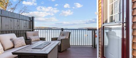 A deck with a sofa and chairs, a table, and a view of the water.