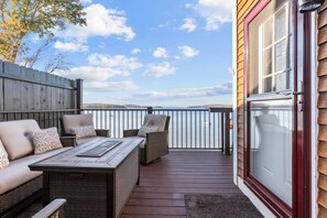 Una terraza con sofá y sillones, una mesa y vistas al agua.