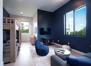 Ein modernes Wohnzimmer mit Fernseher, Sitzgelegenheiten, einem Couchtisch und Blick ins Freie.