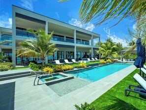 Ein modernes Hotel mit Pool, Liegestühlen und Palmen.