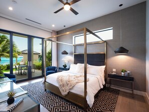 Ein modernes Schlafzimmer mit einem Himmelbett, einer Glastür, die auf einen Balkon führt, und Blick aufs Meer.