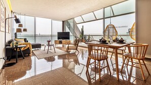 A spacious living area with a large window, a flat-screen TV, a dining table with chairs, and a staircase leading to an upper level. - Casa Reforma by Kukun  (Mexico City)