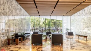 A modern lobby with marble floors, leather seating, and large windows offering a view of the outdoors. - Casa Reforma by Kukun  (Mexico City)