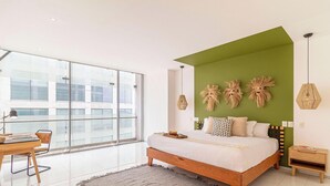 A modern bedroom with a large window, a bed with a green accent wall, and a desk with a lamp. - Casa Reforma by Kukun  (Mexico City)