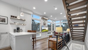 A modern kitchen with white cabinetry, a central island, and a dining area with wooden furniture.