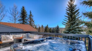 Ein Whirlpool mit Holzterrasse, einer Couch und einem Kamin.