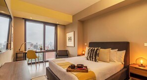 Une chambre d’hôtel avec un grand lit, un bureau, une chaise et une vue sur la ville.