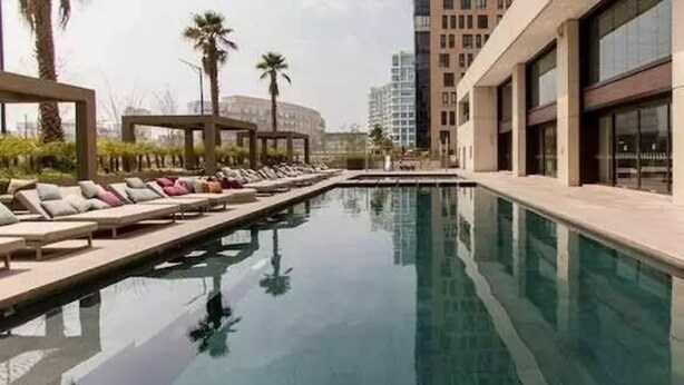 A swimming pool with lounge chairs and palm trees. - Miyana by Kukun (Mexico City)