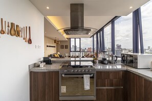 Eine moderne Küche mit Herd, Backofen und großen Fenstern, die einen Blick auf die Stadt ermöglichen.